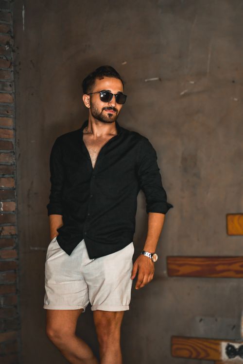 Free Fashionable man in sunglasses posing against an urban wall in casual attire. Stock Photo