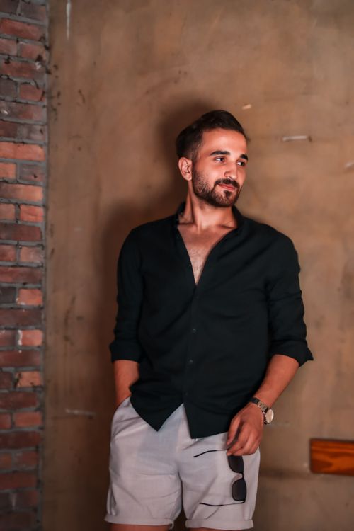 Free Stylish man in casual attire posing indoors against a brick wall. Stock Photo