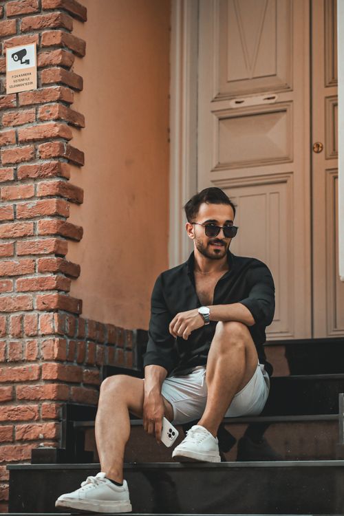 Free Fashionable man in sunglasses sitting on urban steps, exuding confidence. Stock Photo