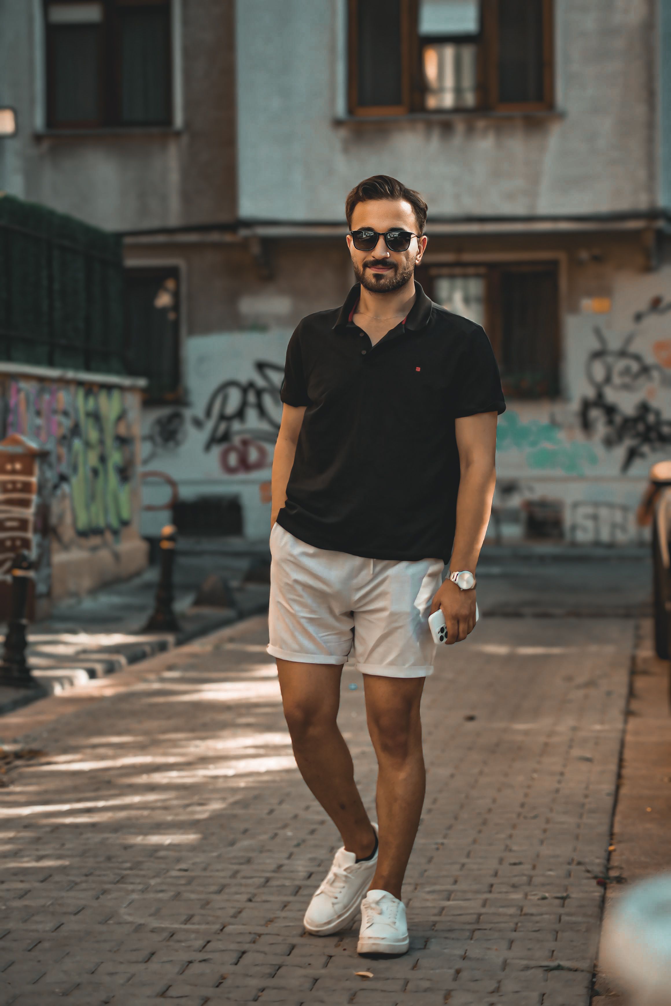 A man in black polo shirt and white shorts standing on a street · Free ...