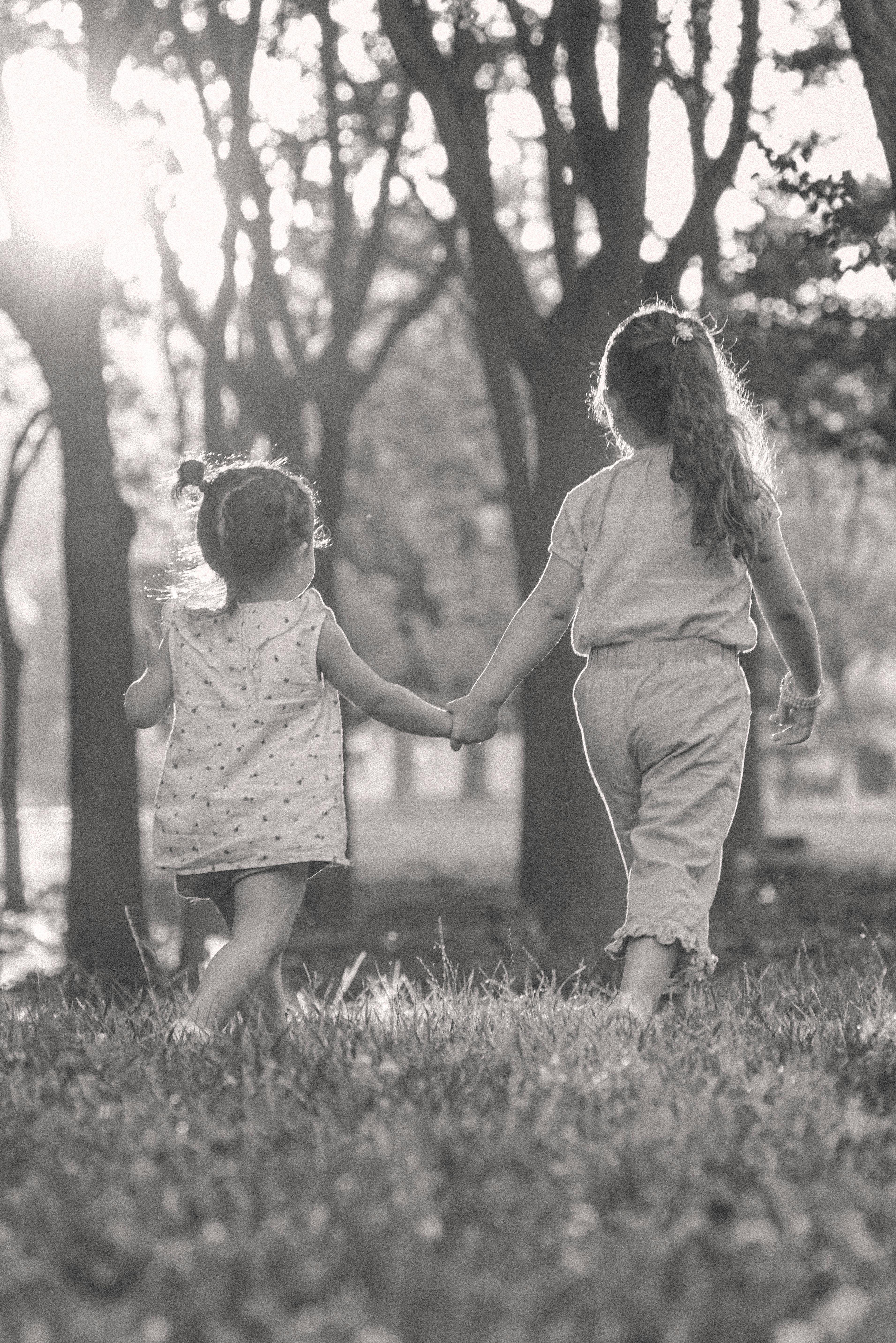 Two children walking hand in hand in a sunlit park, creating a warm family moment.