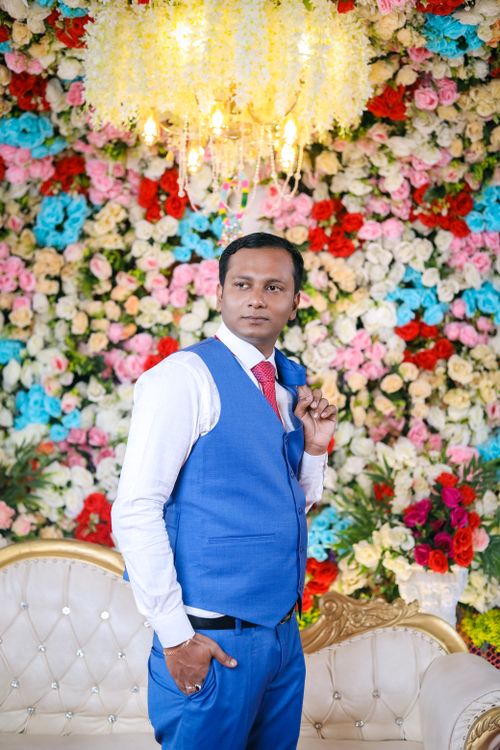 Free Elegant groom poses with floral backdrop at Indian wedding, showcasing vibrant colors and traditional attire. Stock Photo