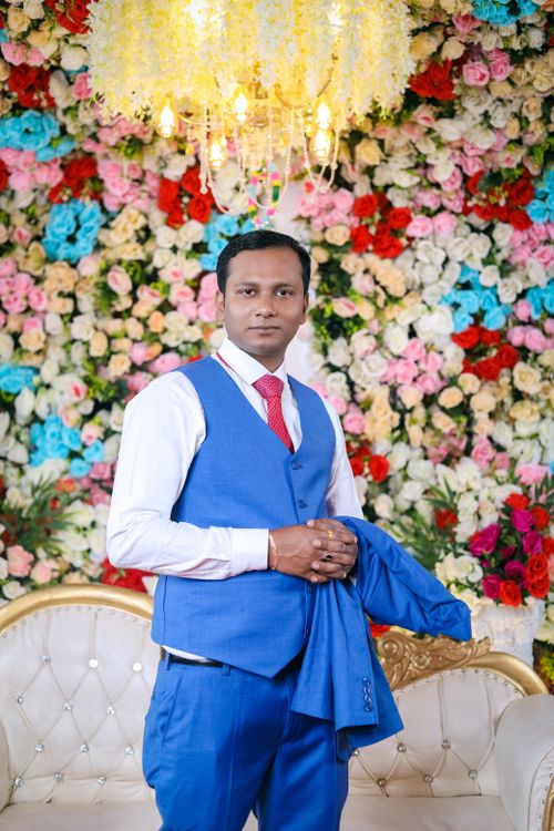 Free Man in blue suit poses at Indian wedding with colorful floral background. Stock Photo