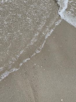 Serene beach scene with gentle waves washing over sandy shore, perfect for relaxation themes.