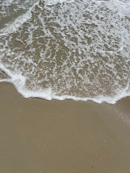Gentle ocean waves meeting a sandy beach, creating a serene and peaceful atmosphere.