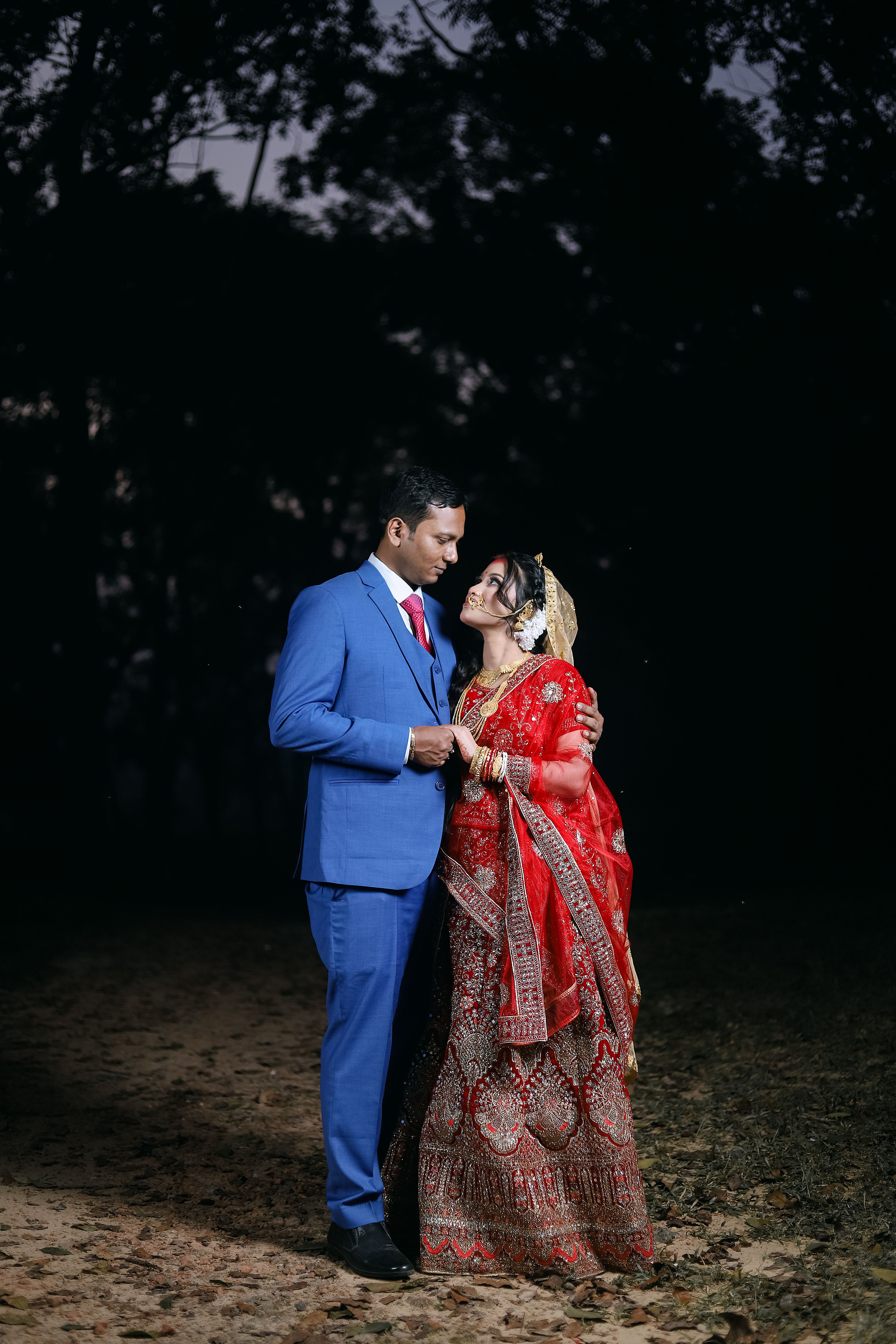 A couple in traditional attire standing in the dark · Free Stock Photo