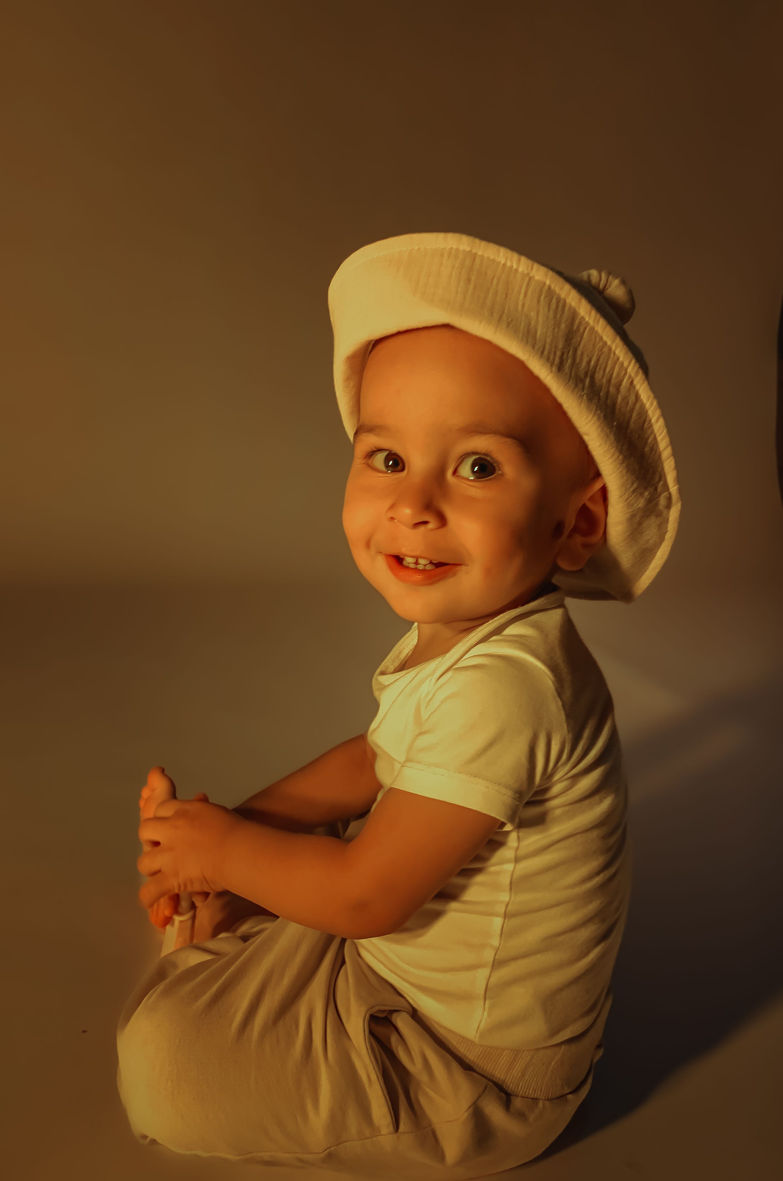 Adorable child wearing a hat, captured in a warm and playful setting.