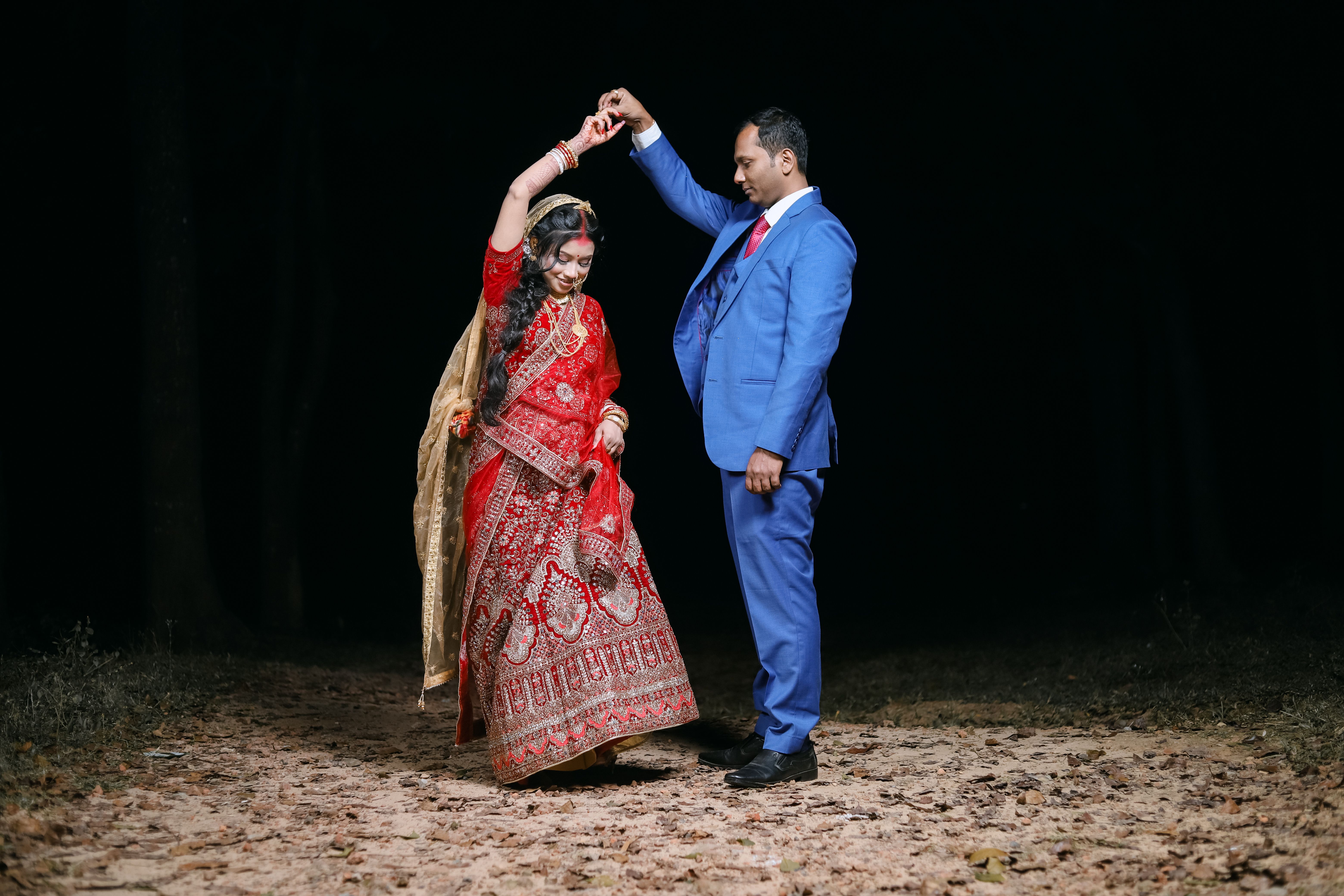 A couple gracefully dances during a nighttime Indian wedding, adorned in traditional attire.