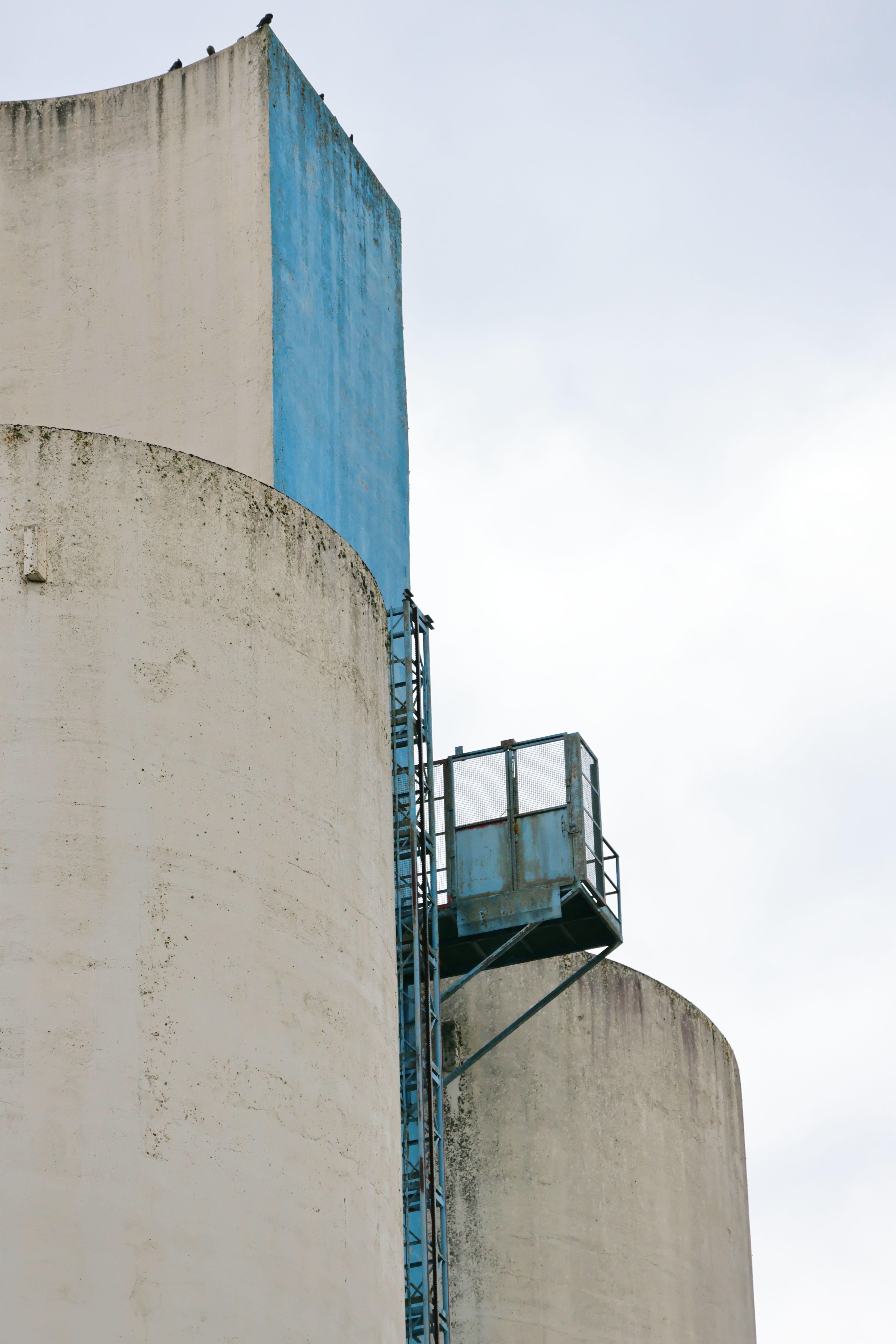 Close-up view of tall concrete silos with industrial scaffolding, set against an overcast sky.