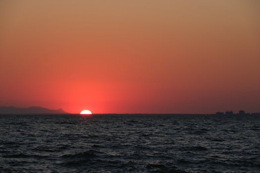 Beautiful sunset over the ocean with a mesmerizing red sky, perfect for serene and peaceful moments.