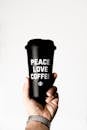 一只手拿着咖啡杯的特写，杯上写着“和平爱咖啡”的文字，传递着积极向上的氛围