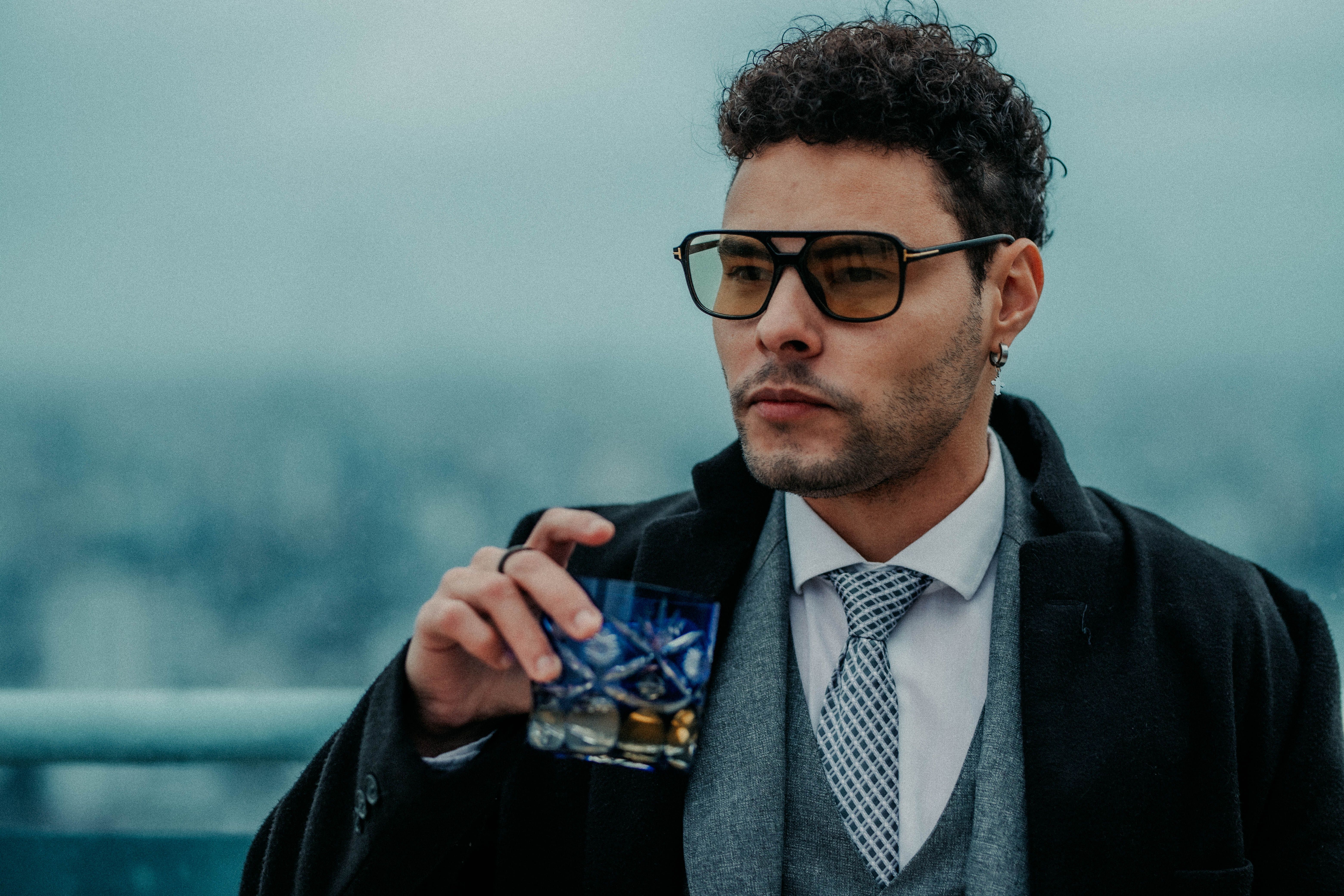 A man in a suit holding a drink · Free Stock Photo