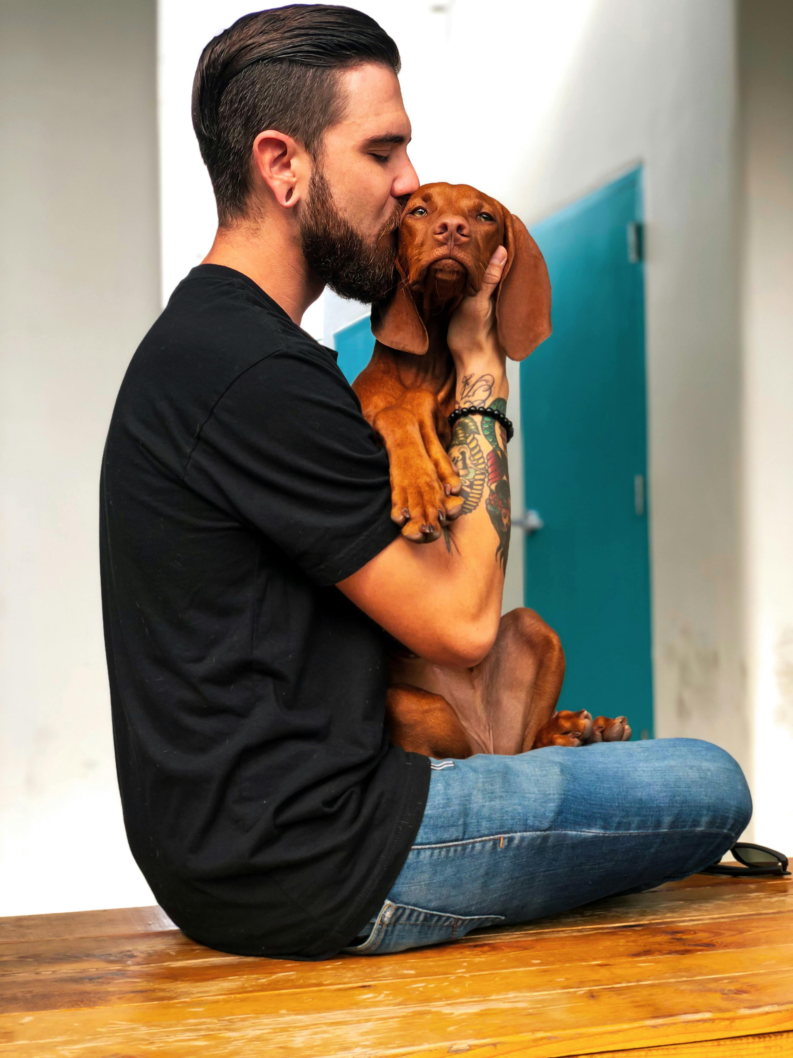 photo of man kissing his dog