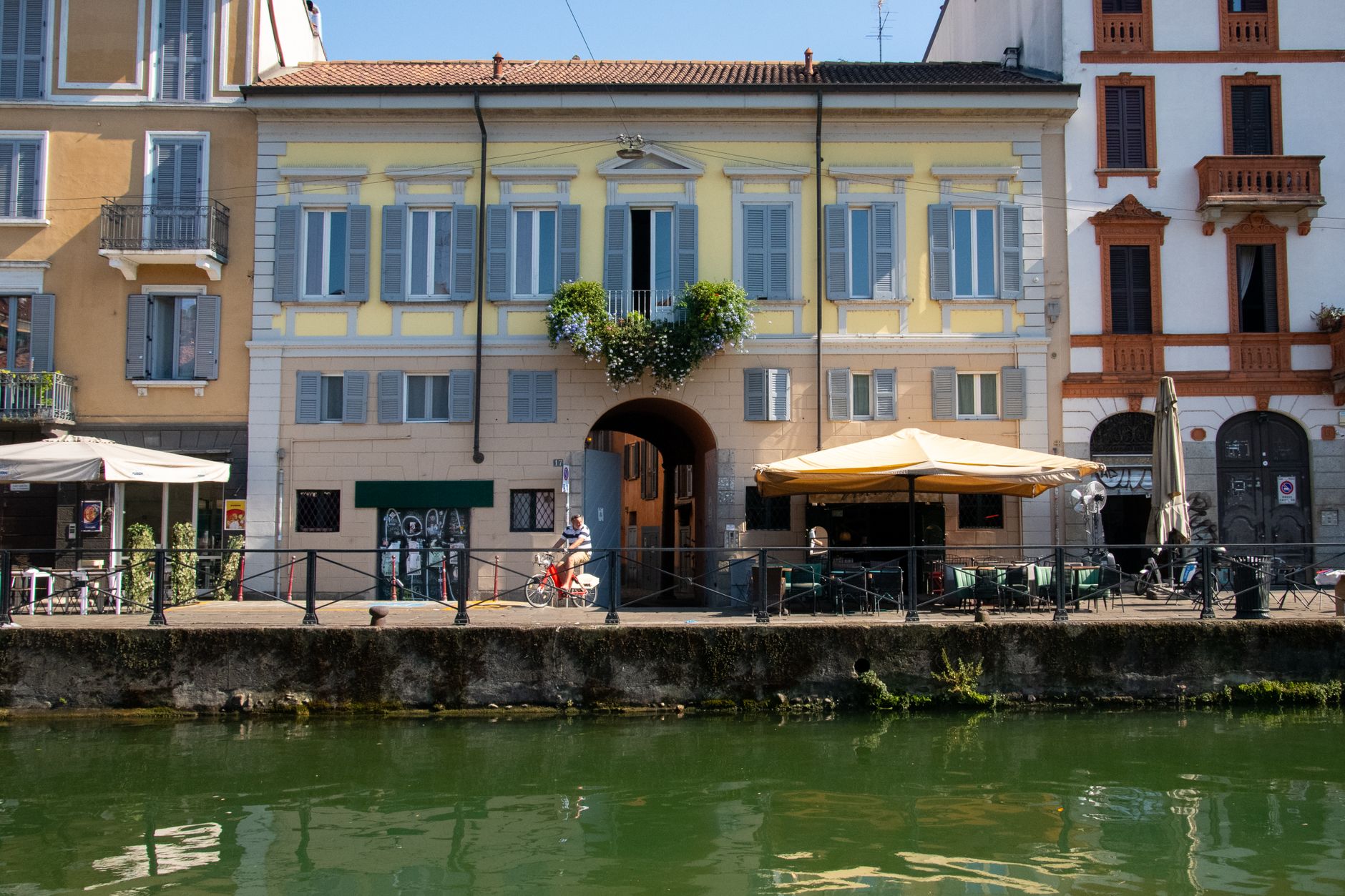 Picturesque canal view in Milan's Navigli District showcasing vibrant buildings and outdoor cafes.