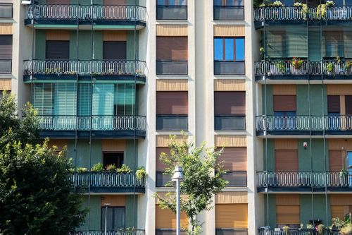 Free Contemporary apartment facade with glass balconies and green accents, capturing urban residential life. Stock Photo
