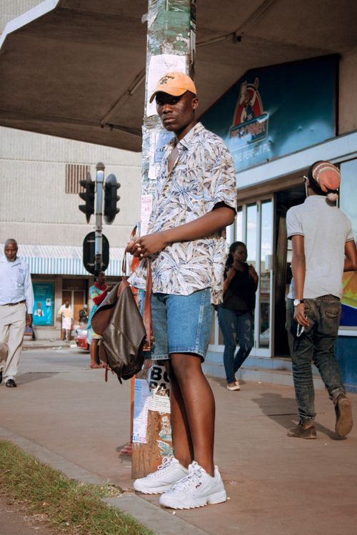 Free Fashionable man stands in Bulawayo city wearing a Hawaiian shirt and cap, embodying urban street style. Stock Photo