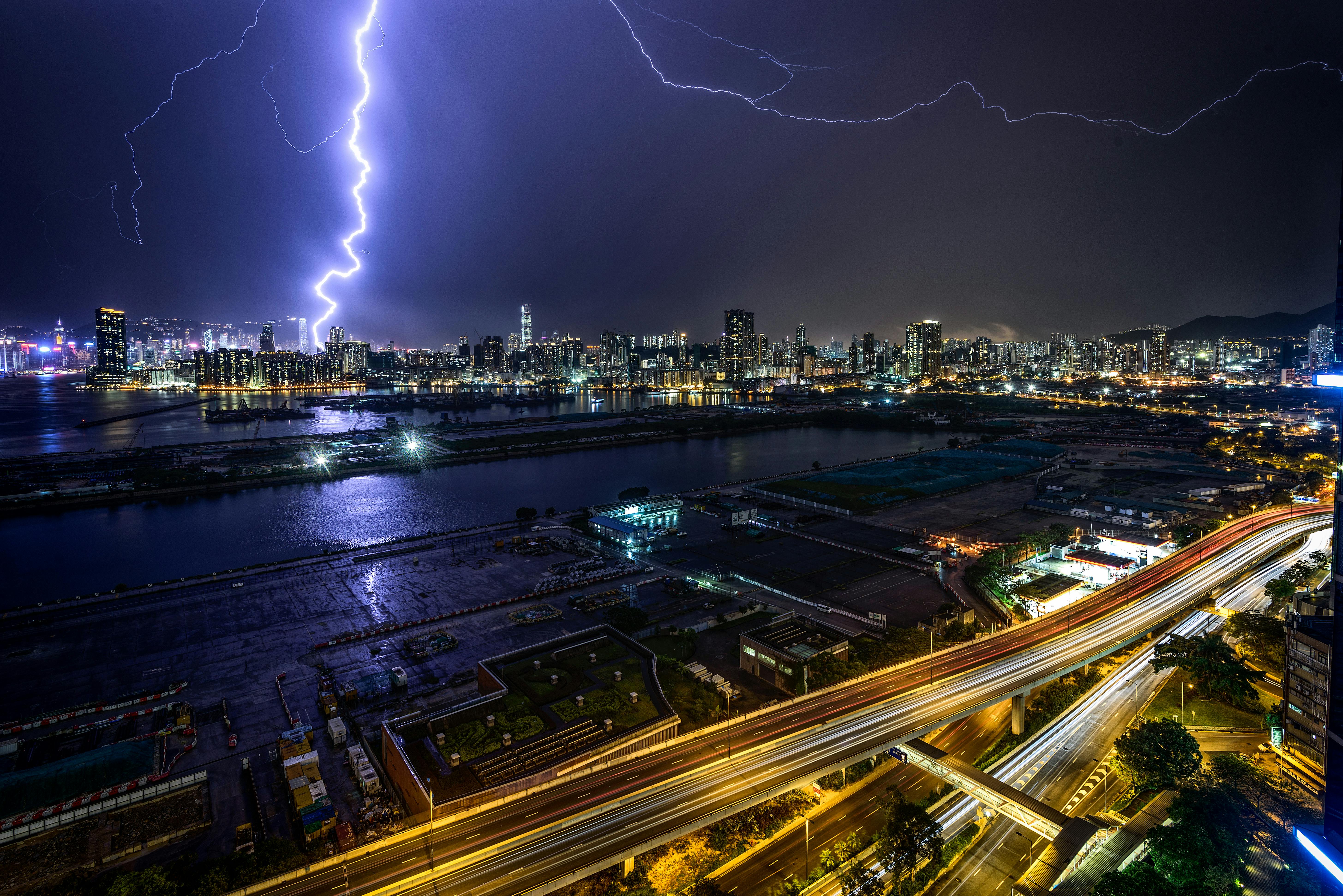 time lapse photography of lightning above lighted buildings during night