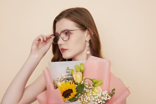 Portrait of a stylish woman with glasses holding a vibrant floral bouquet.