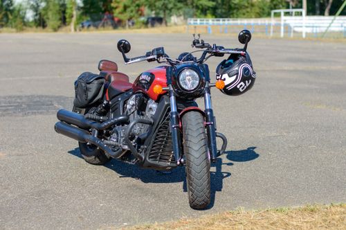 Free A classic red motorcycle parked outdoors with a helmet on the handlebars. Stock Photo