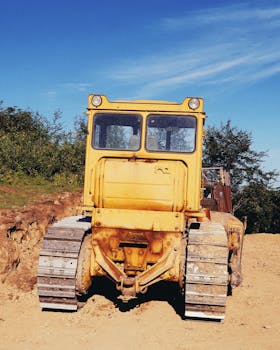 Bright yellow bulldozer at a sunny outdoor construction site with clear blue skies.