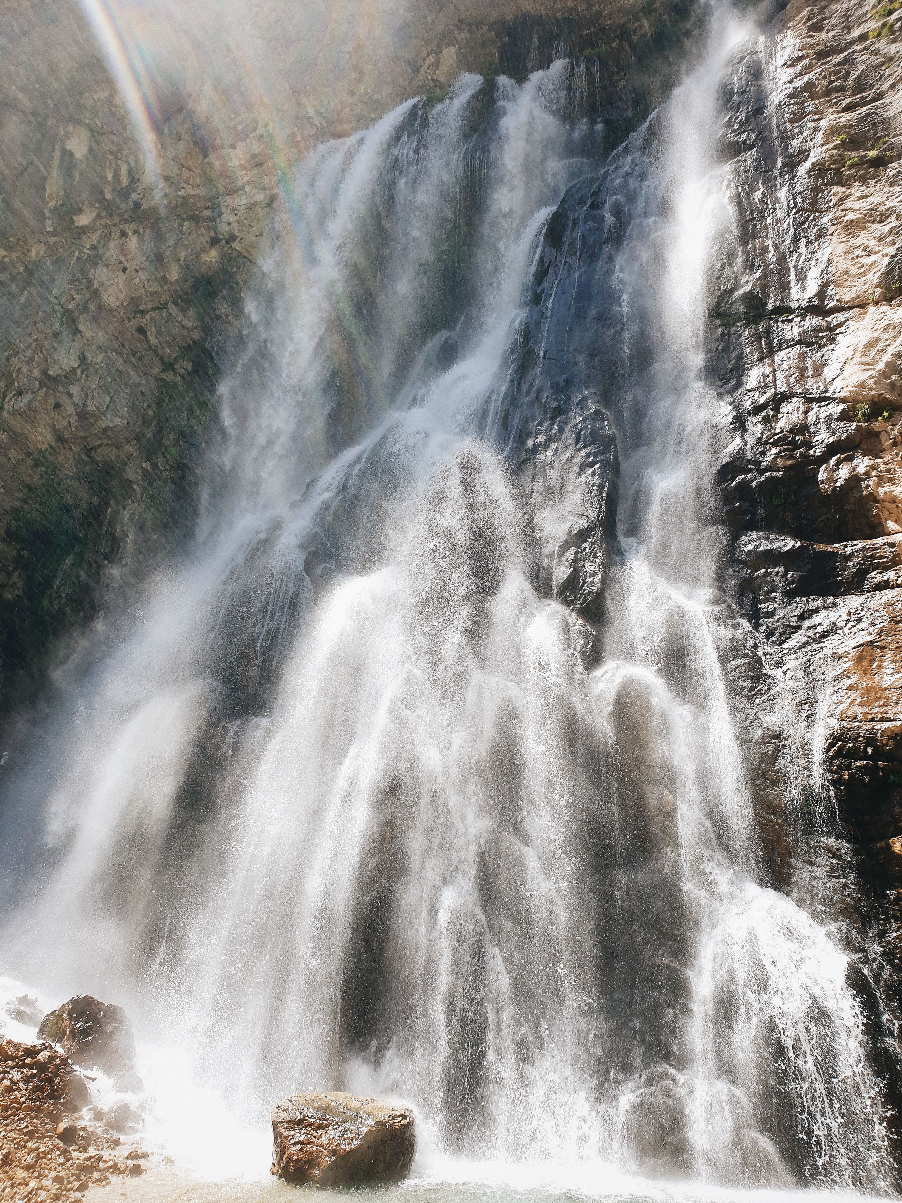 A waterfall with the sun shining through it · Free Stock Photo