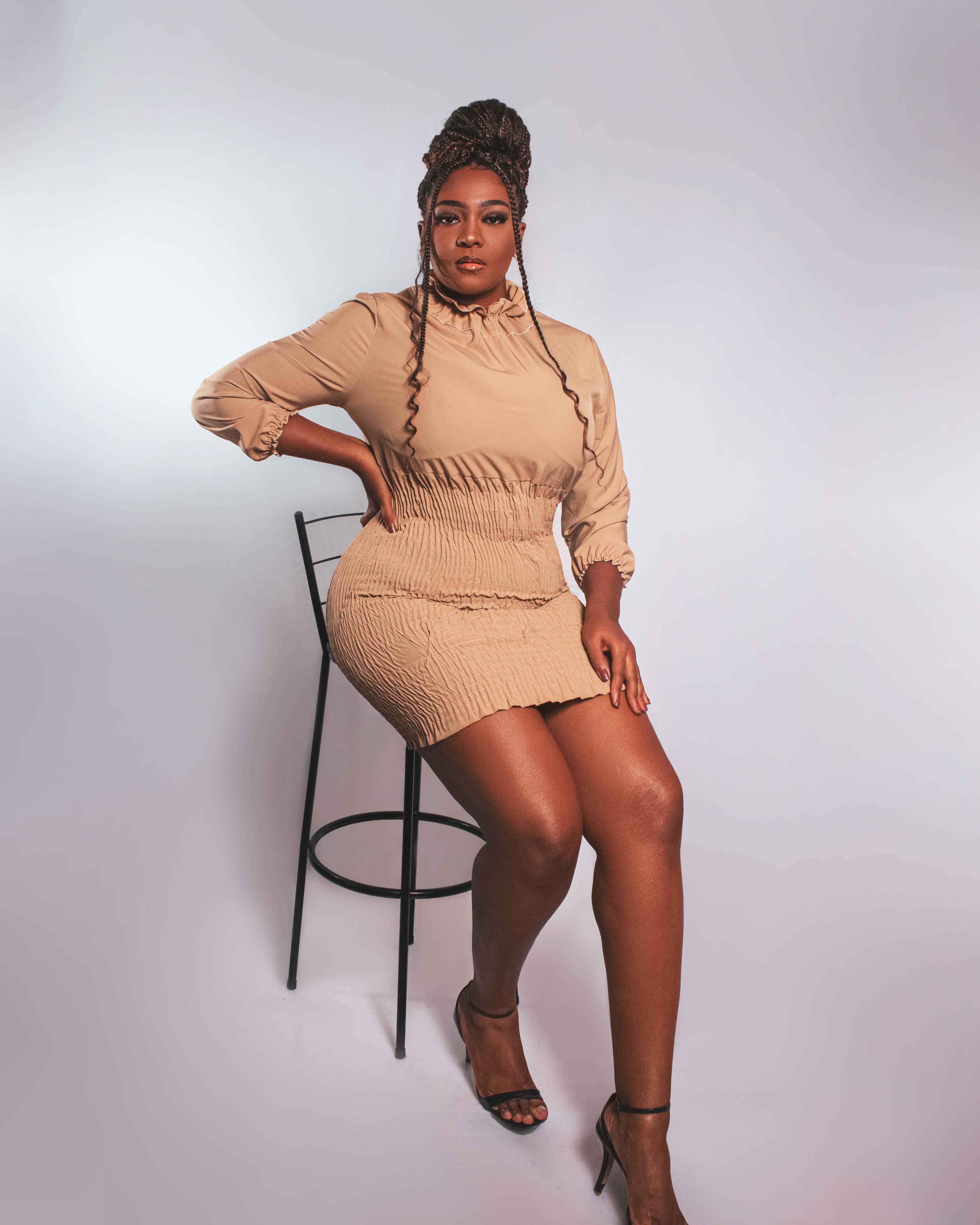 A woman in a tan dress sitting on a chair · Free Stock Photo