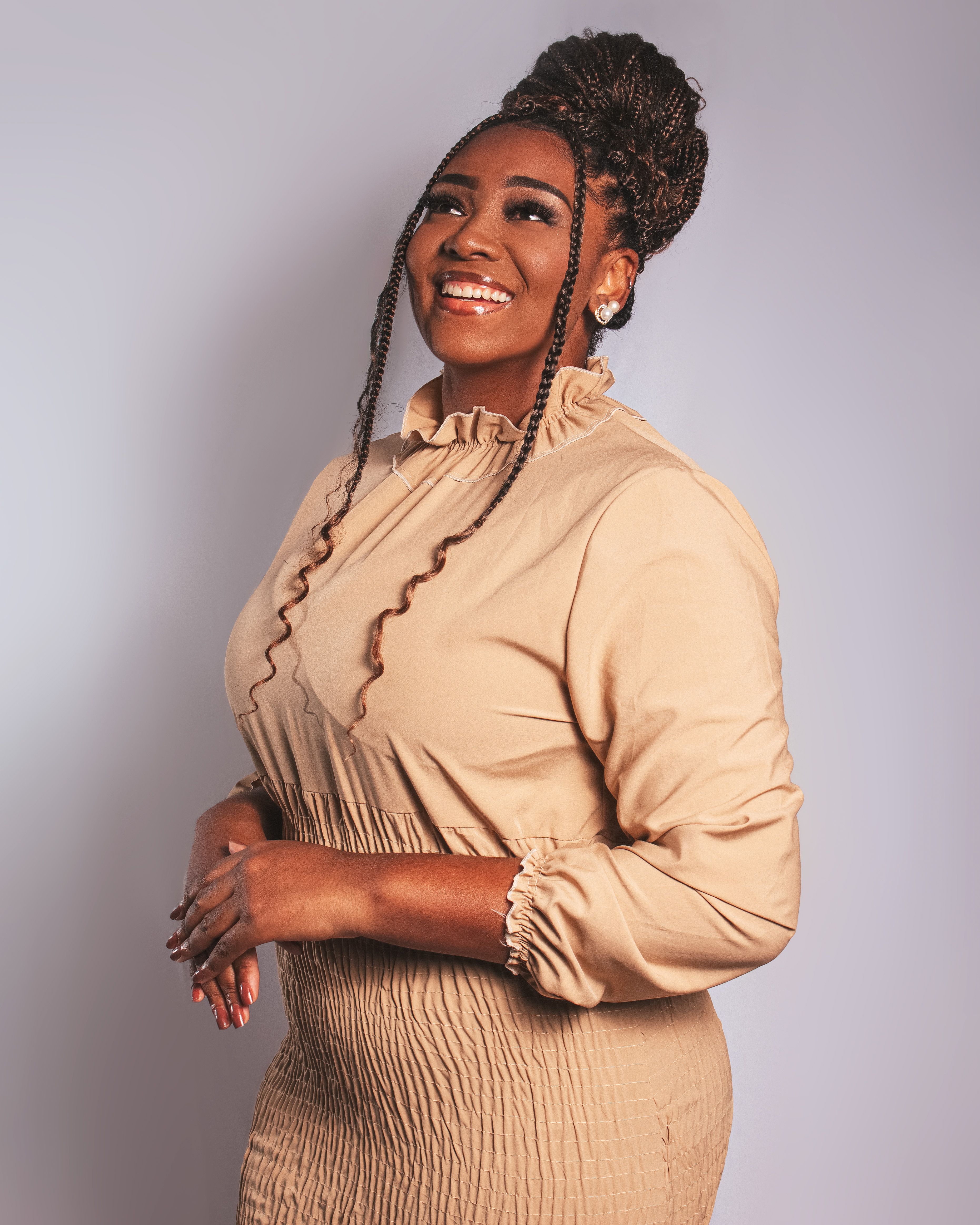 A joyful woman in a beige dress, exuding elegance and confidence.