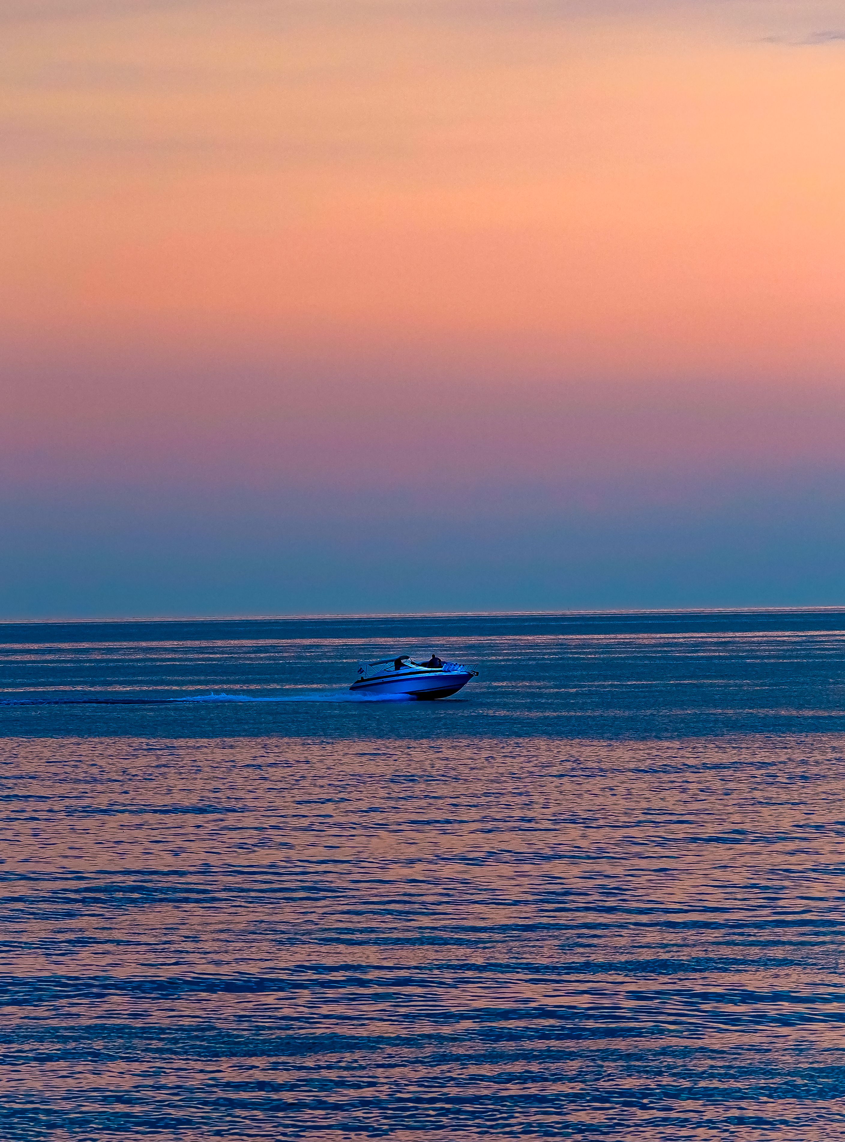 A boat is traveling on the ocean at sunset · Free Stock Photo