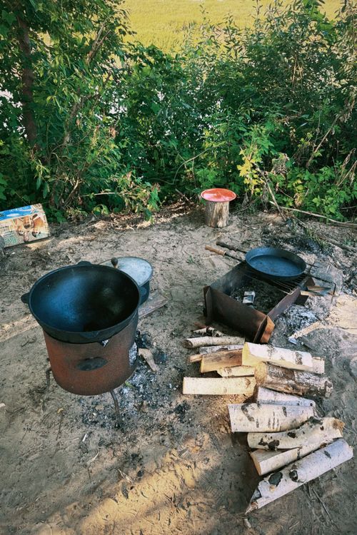 Free Outdoor cooking scene with pots and firewood in a forested area, ideal for rustic cuisine. Stock Photo