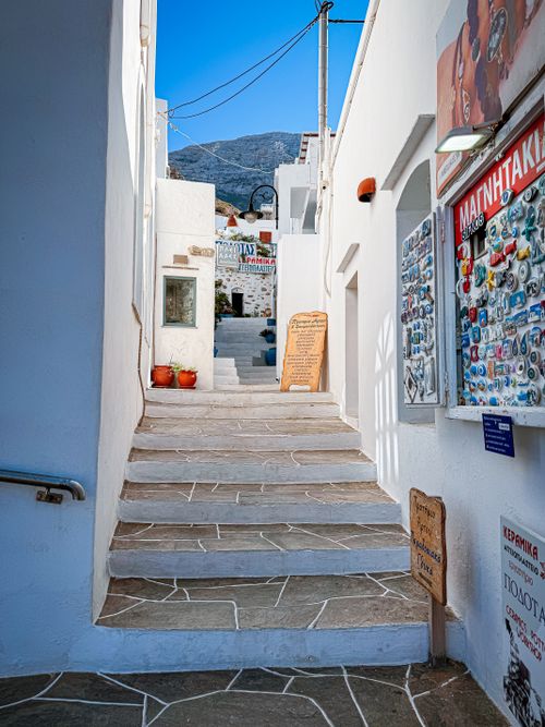 Free Explore a quaint alleyway in a Greek island town with whitewashed buildings and blue accents. Stock Photo