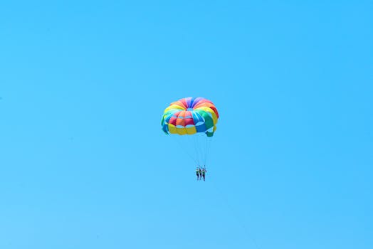 Colorful parasailing with two people high in the clear blue sky enjoying a thrilling adventure.