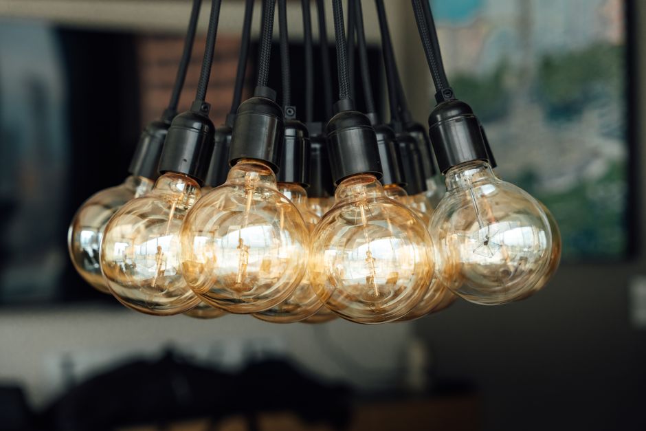 Myth-Busting Smart Bulbs vs Smart Switches: What Works Best in 2026 Warm glowing vintage light bulbs hanging indoors, creating an industrial and cozy ambiance.