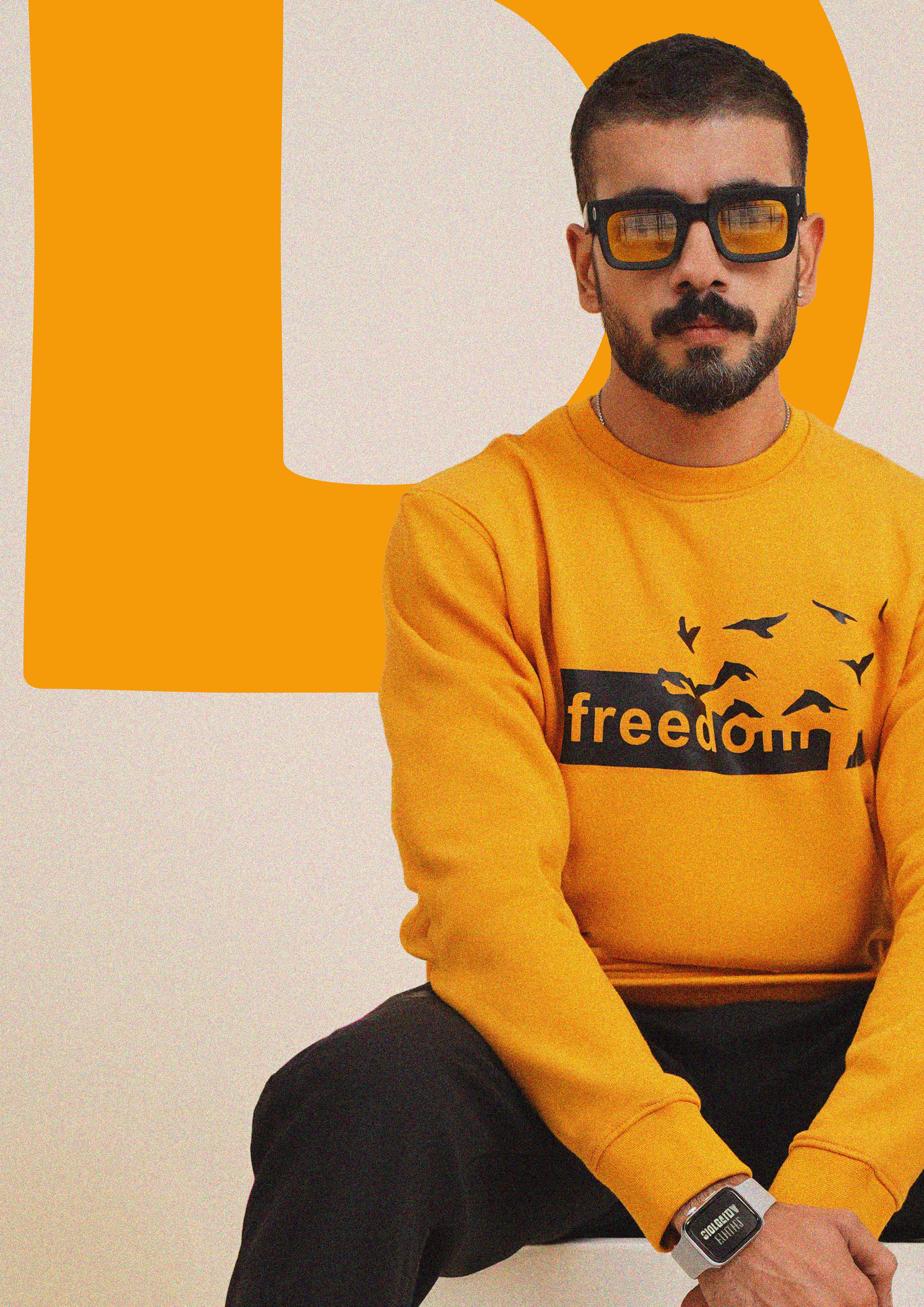 Fashionable man in yellow sweater, wearing sunglasses indoors with a trendy style.