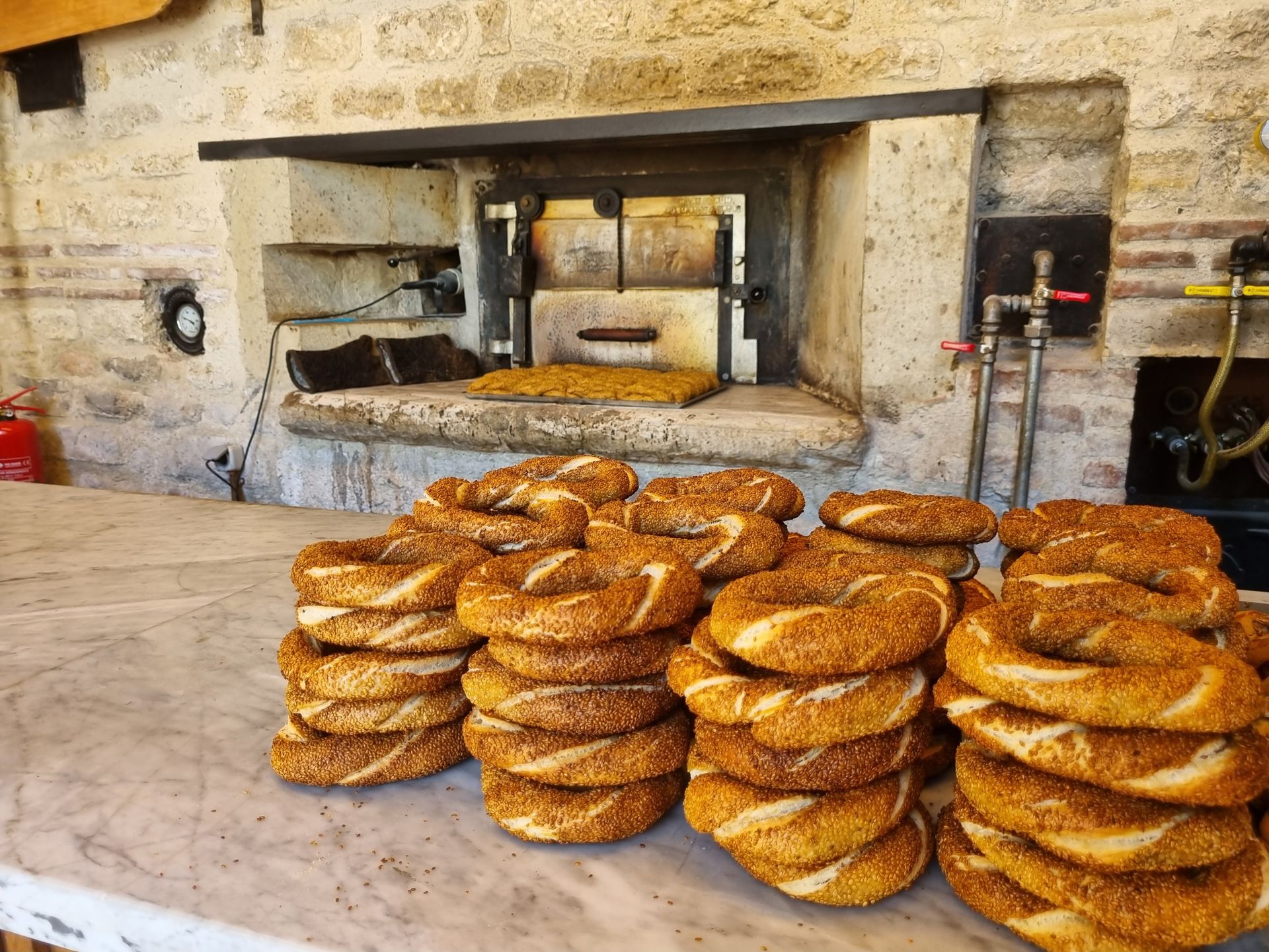 Freshly baked sesame bread rings in a rustic stone oven bakery, showcasing traditional baking methods.