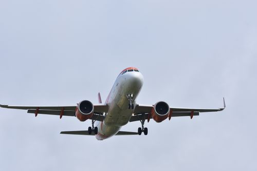 Free A commercial airplane captured mid-air, showcasing its wings and engines against a clear blue sky. Stock Photo