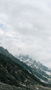 Breathtaking view of snow-capped mountains under a cloudy sky in Naran, Pakistan.