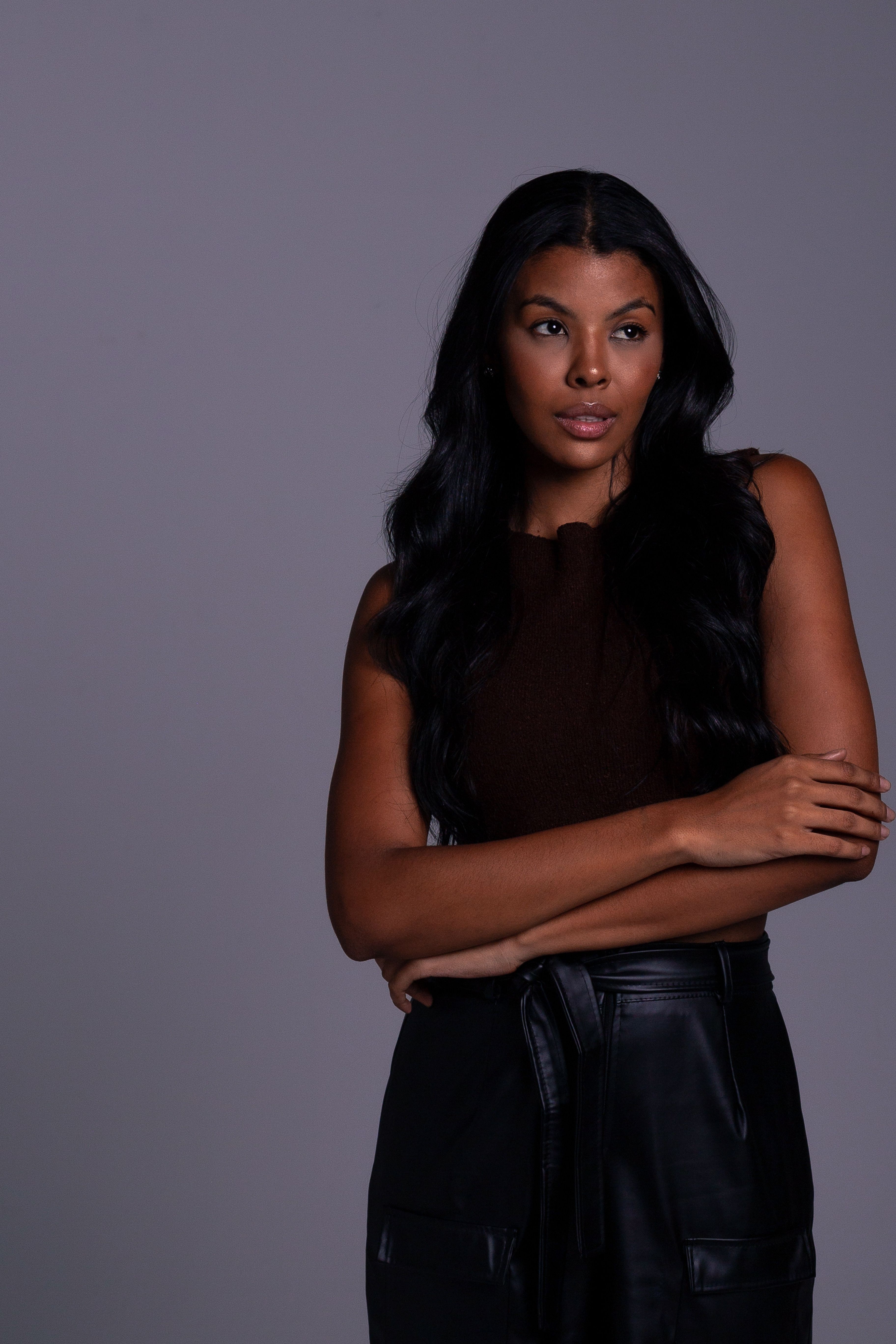 Portrait of a young woman with dark hair in a studio setting, exhibiting elegance and style.
