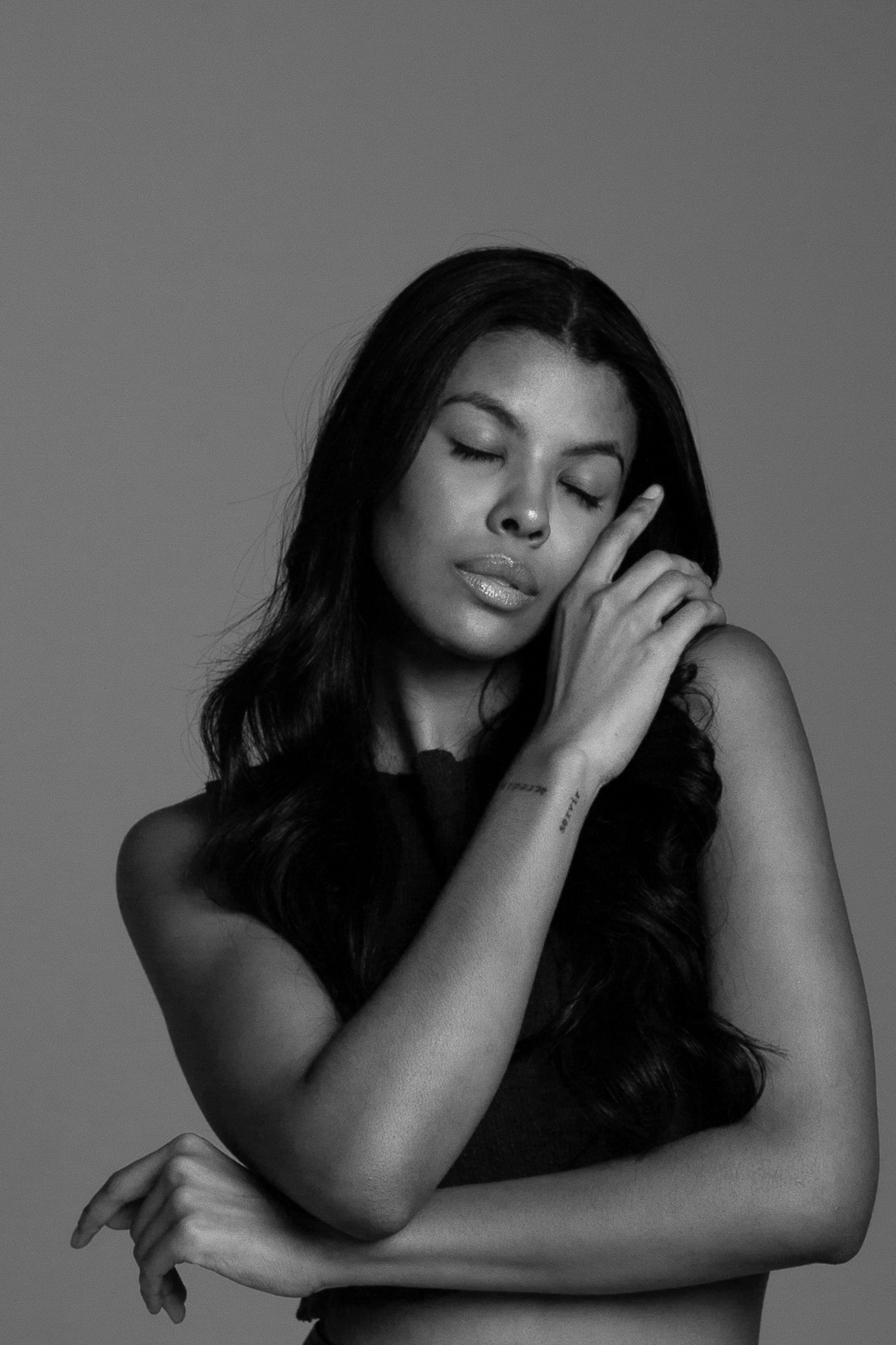 Elegant black and white studio portrait of a woman with closed eyes and long dark hair.