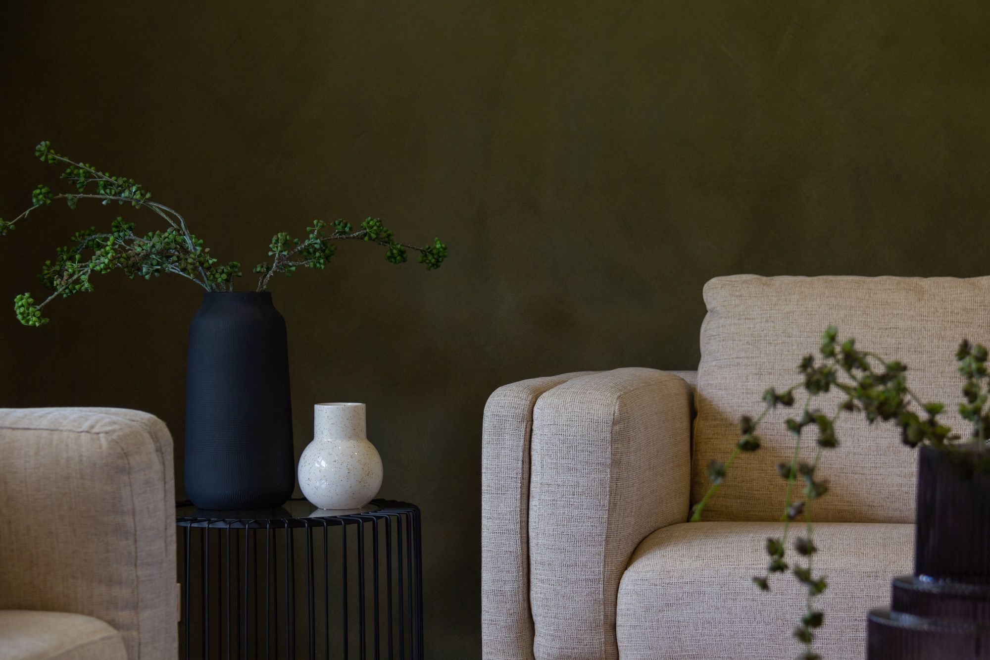 Warme woonkamer in olijfgroen met crème fauteuils en planten
