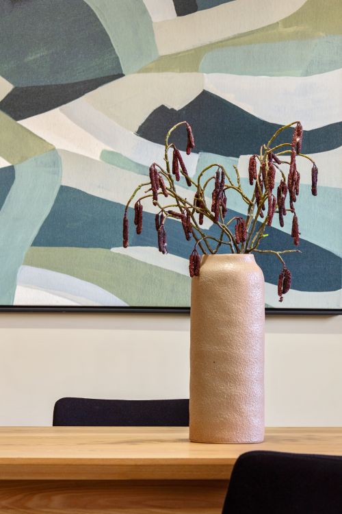 Free A contemporary vase with dried flowers sits on a wooden table in a modern interior with abstract art. Stock Photo