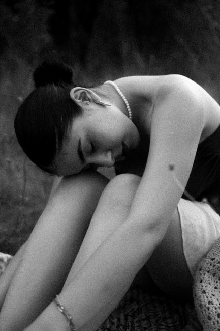 Black and white portrait of a woman sitting gracefully in introspection.