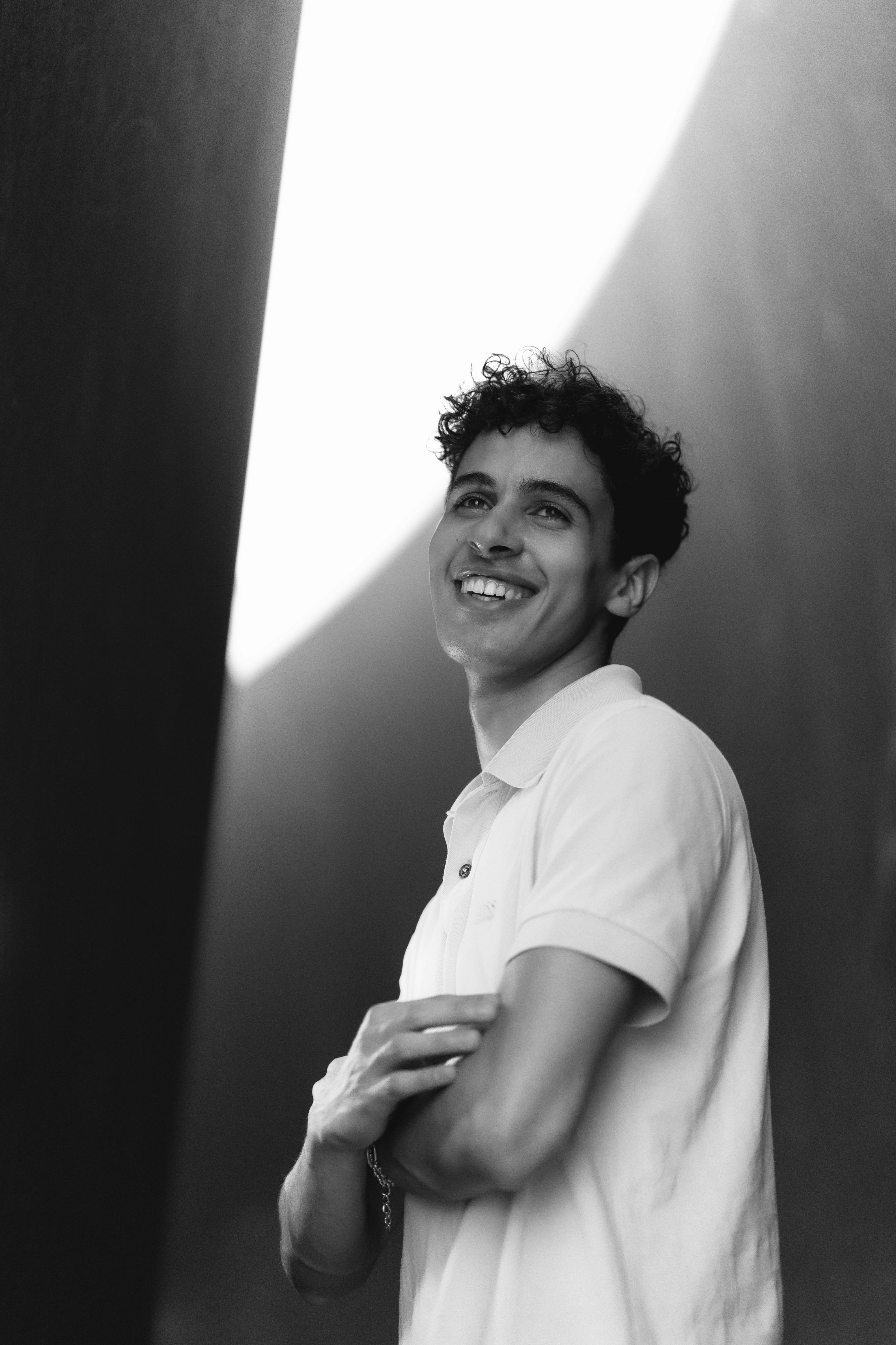 Black and white portrait of a young man smiling indoors, taken in Berlin.