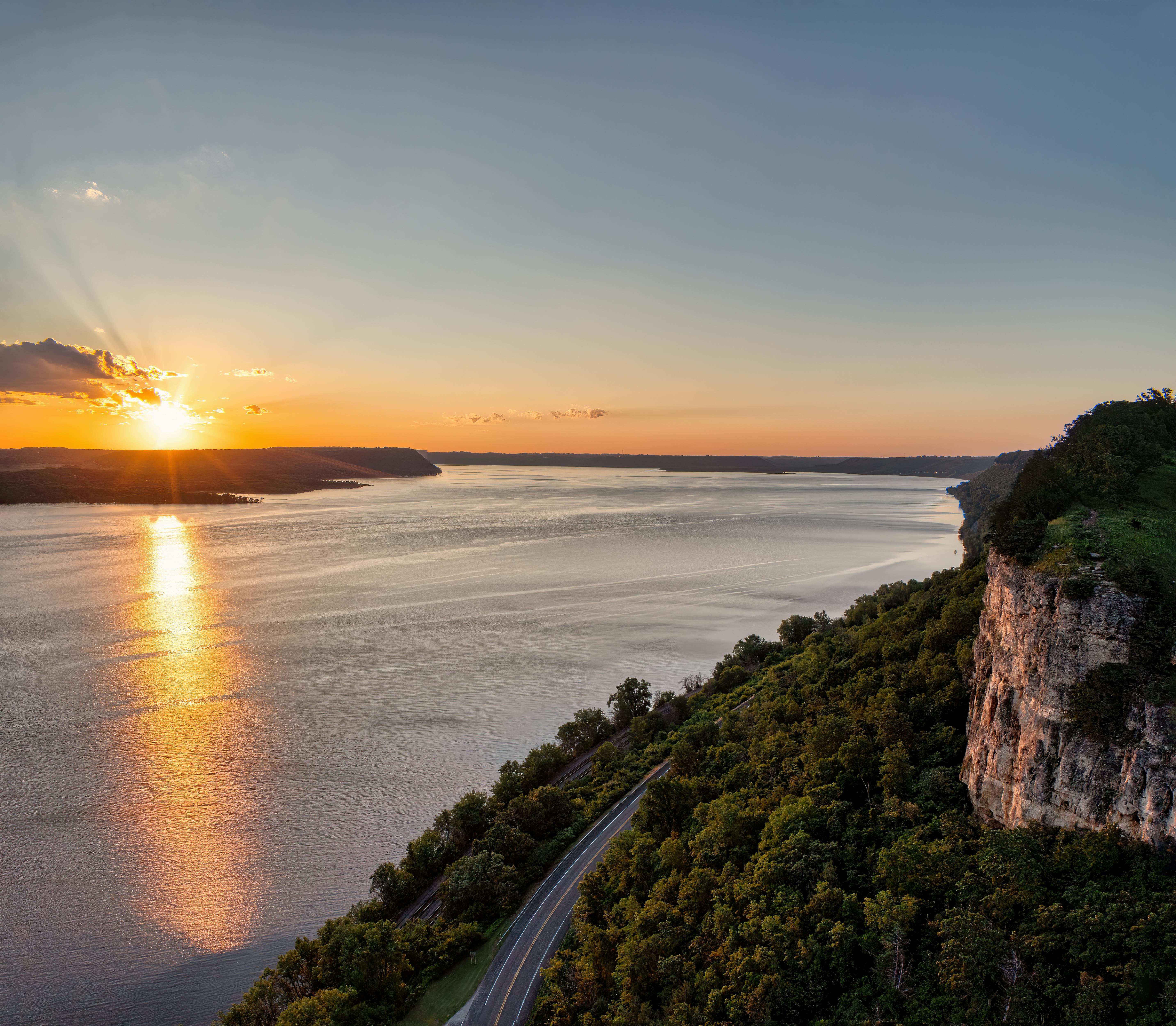 a sunset over a river and a road