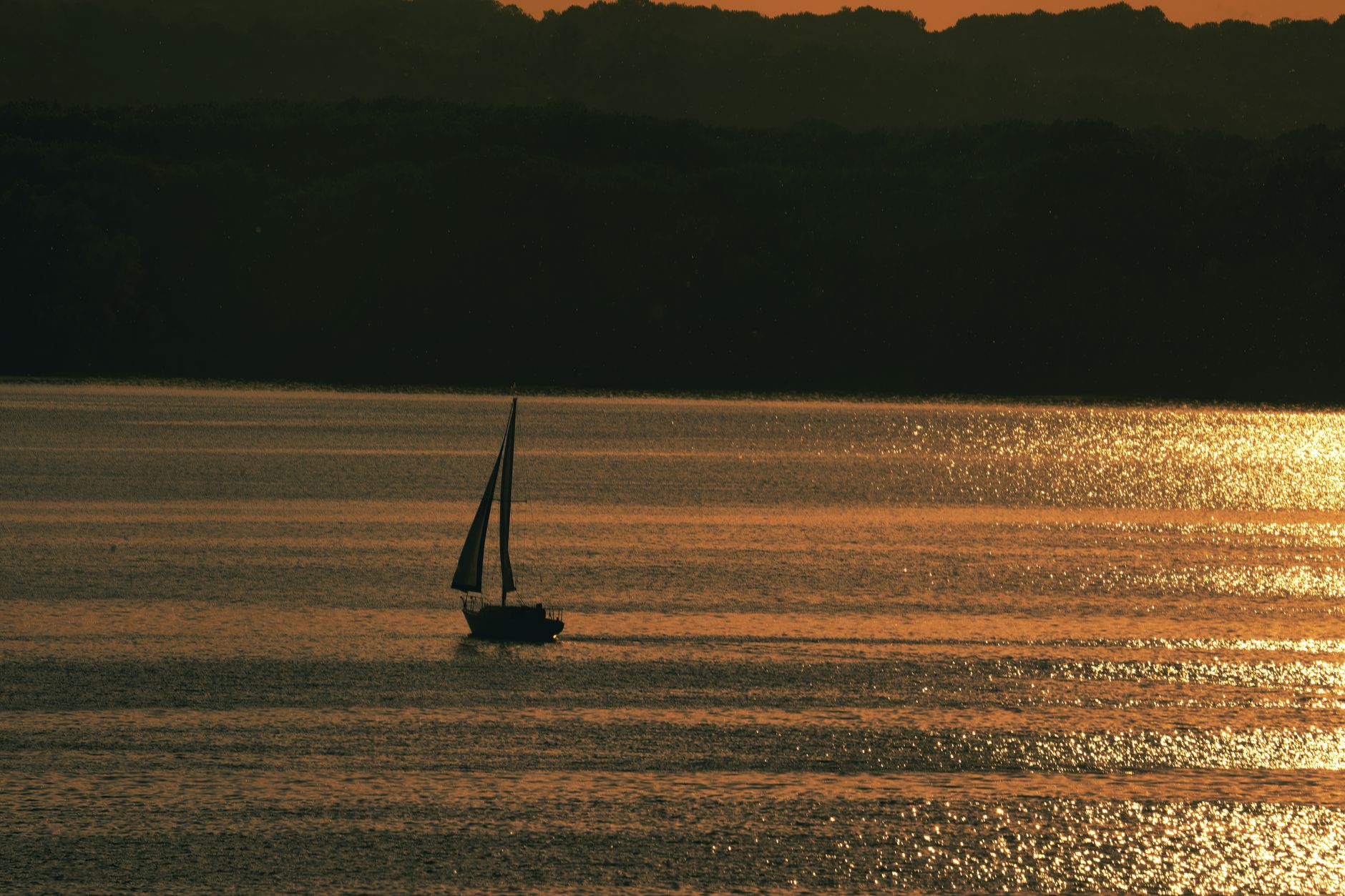 A sailboat silhouetted against a golden sunset on Stockholm, WI waters.