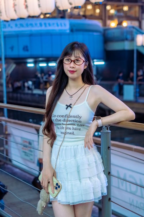 Free Stylish woman in a white dress standing on an urban bridge at night, exuding confidence. Stock Photo