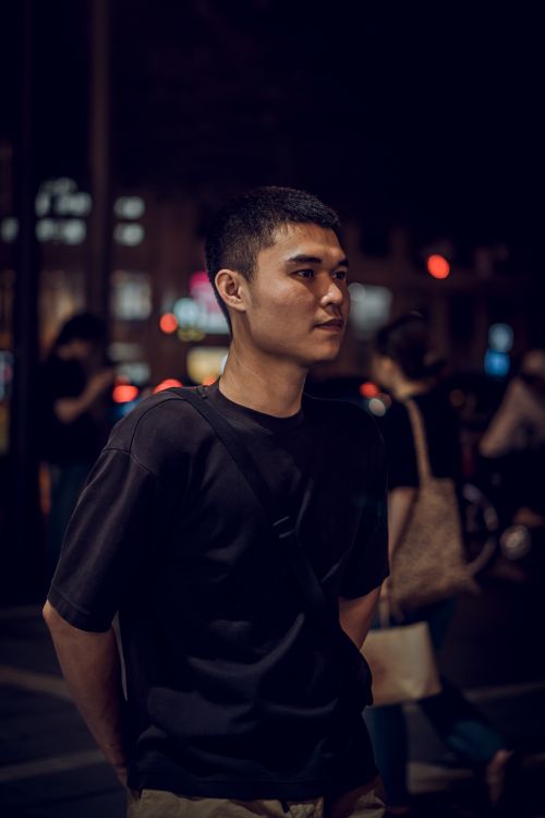 Free Portrait of a young man at night in a vibrant city street setting. Stock Photo