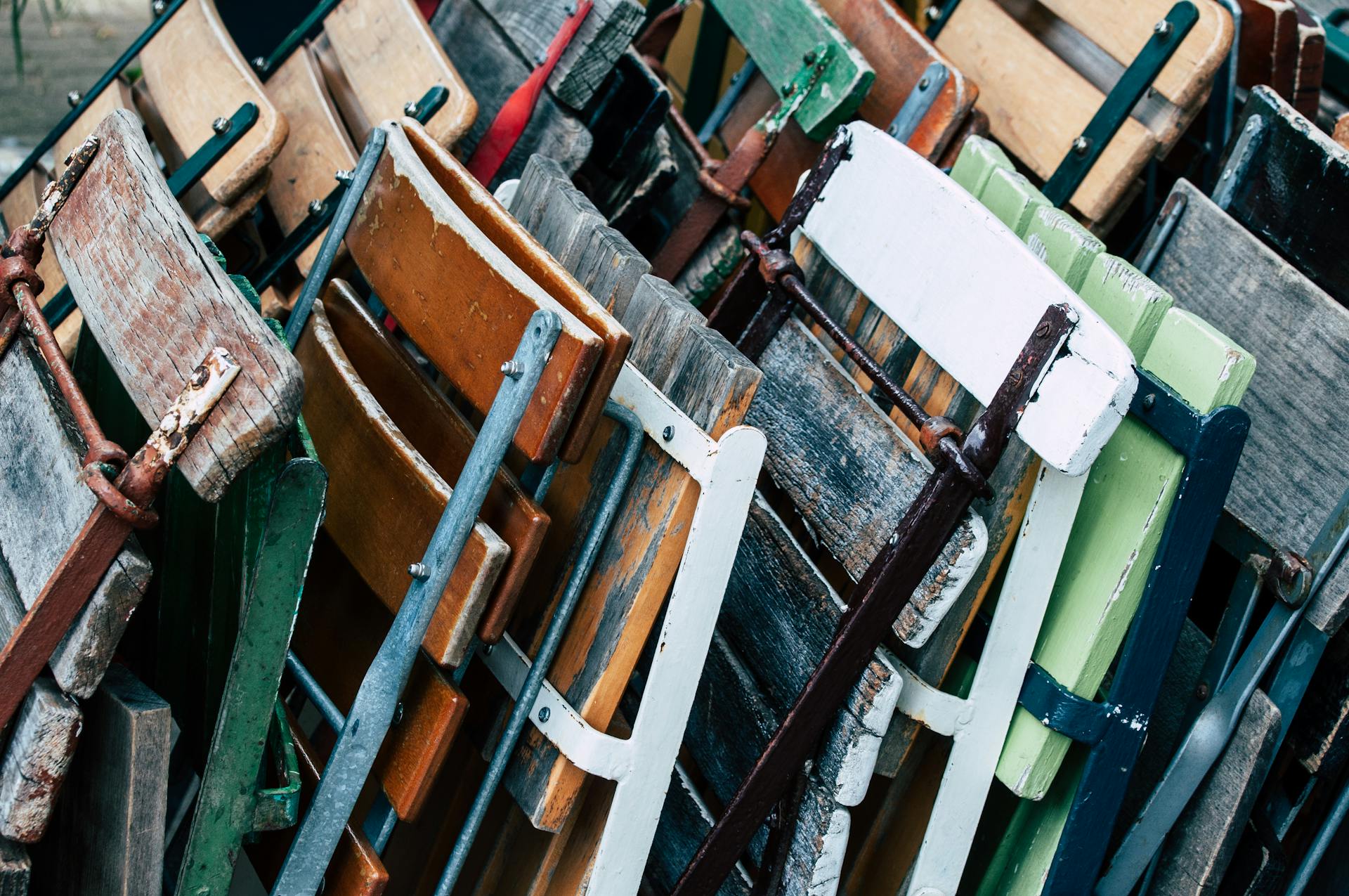 A pile of old wooden chairs with different colors