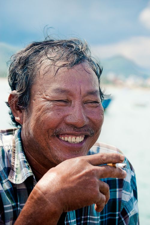 Free Joyful portrait of a Vietnamese fisherman in Nha Trang, smiling with the sea in the background. Stock Photo