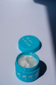 Open blue container of luxurious skincare cream with palm decorations, perfect for moisturizing and health.