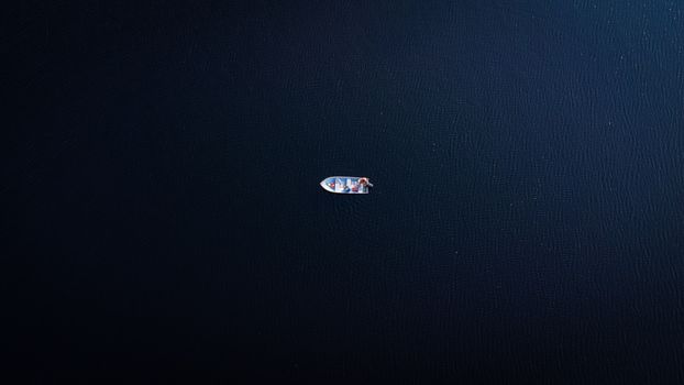 A solitary boat afloat in the calm, deep blue waters of Blackstone Lake, captured from above.